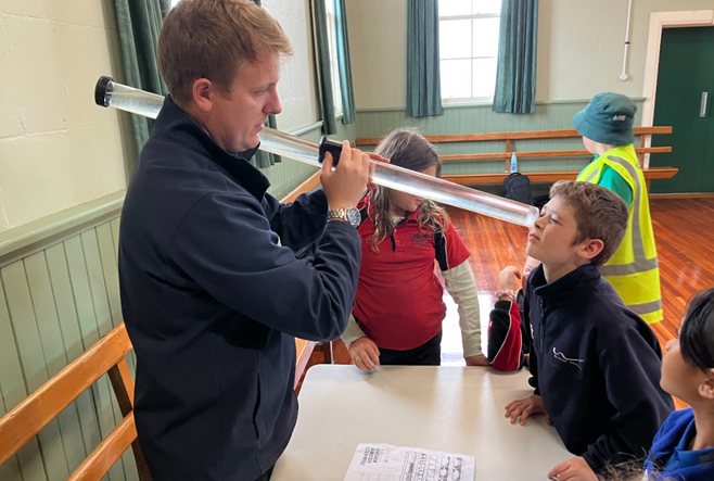 an adult holding a plastic tube with water in it while a child looks through the other end