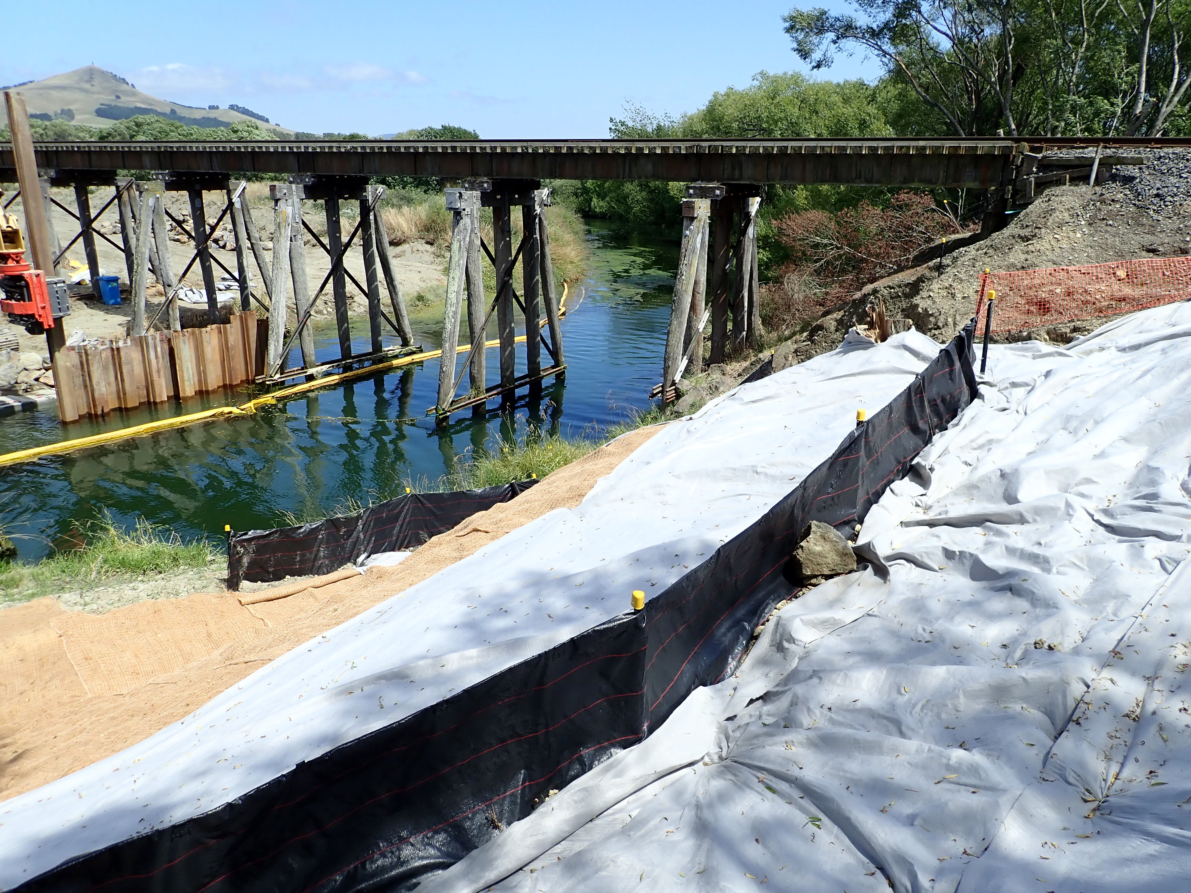Covering exposed soils and silt fences to stop sediment entering water and creation of coffer dam (yellow device in water), to limit area sediment can travel to if it does reach water