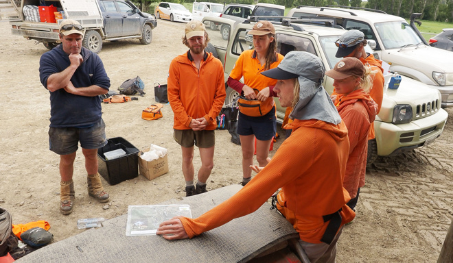 a group of people wearing bright orange tops standing in a car park talking to each other