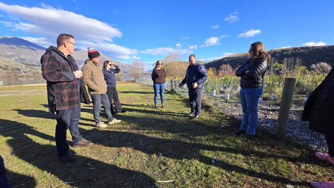 a group of people standing in a field on a sunny day listening to one person talking