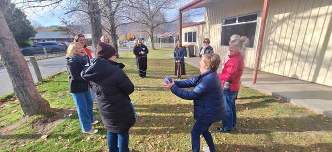 a group of people laughing as they play a game while standing outdoors in a circle