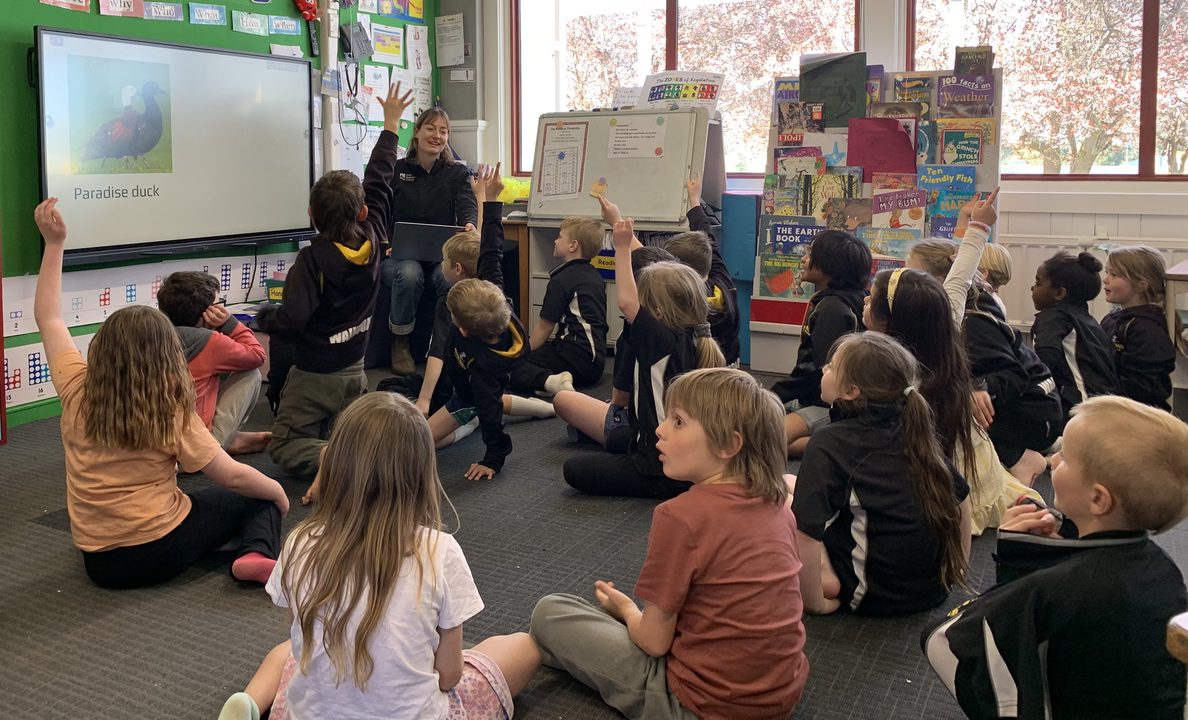 a group of children sitting on the floor inside a classroom
