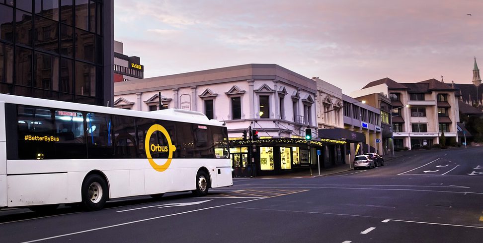 a white bus driving down a city street next to buildings
