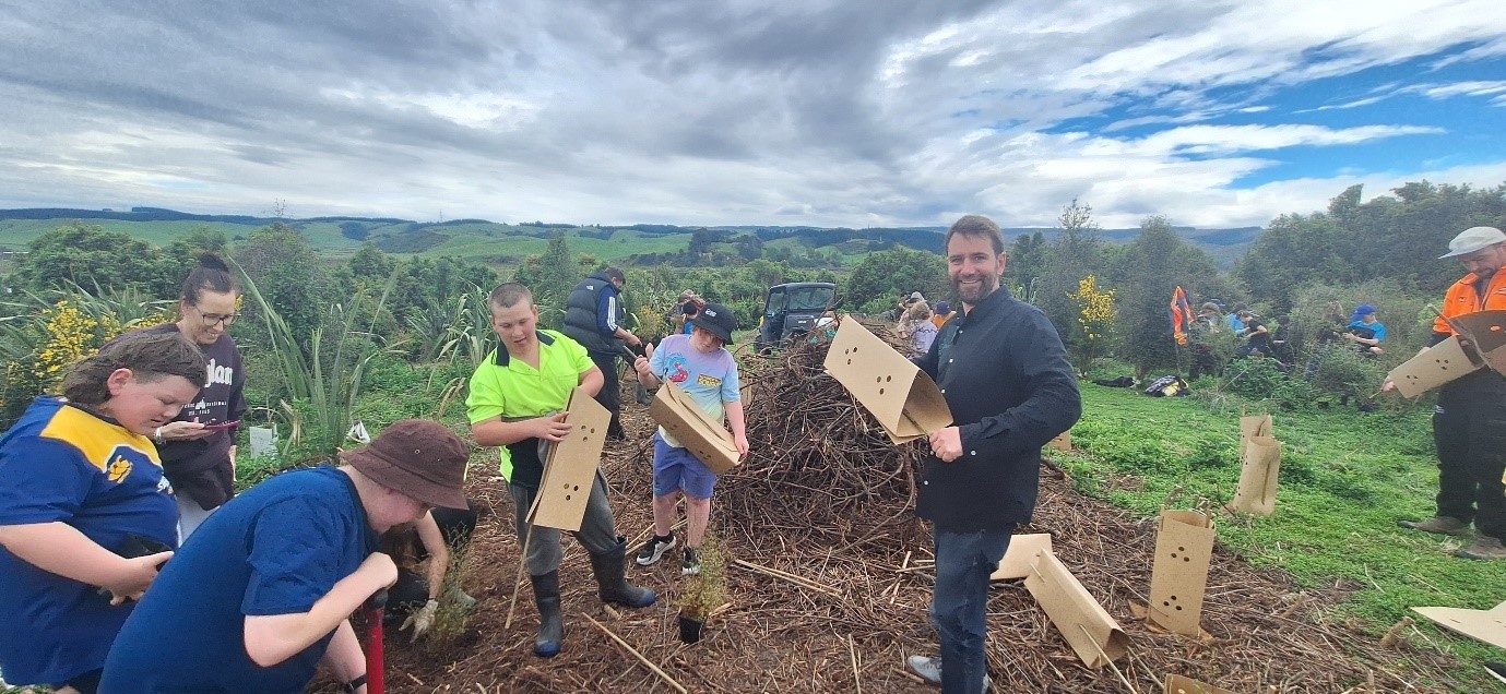 a group of adults and children planting trees in a rural setting