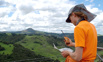 Jamie Standing On A Hill On 4 Rivers Farm Touching Base With Volunteers Over The Radio To Organise Pick Up Locations After Finishing Trapping For The Day. Southern Face Of Hikaroroa Mt Watkin On The Horizon.
