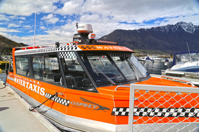 an orange boat docked at a wharf with mountains in the background