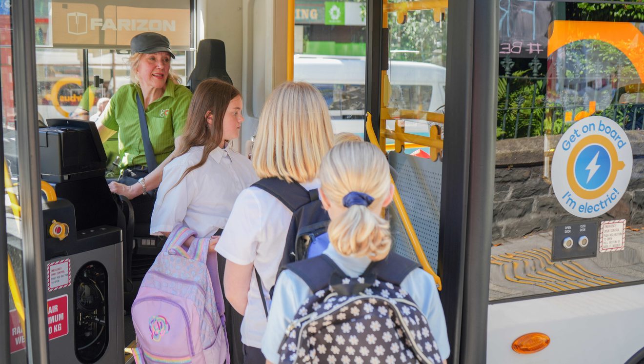 school children boarding a bus as the driver looks on