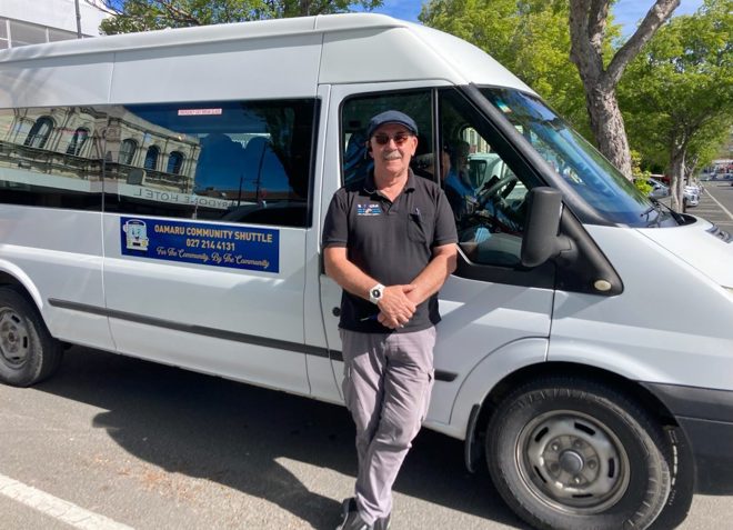 a person wearing sunglasses and a hat standing in front of a white van and smiling at the camera