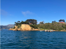 an island with two buildings on it surrounded by the sea