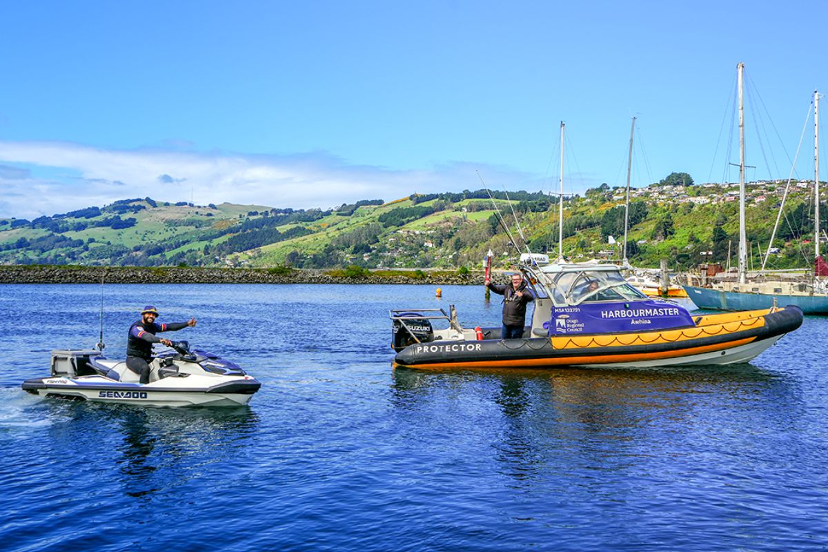 a jetski and a boat in the water on a sunny day with the drivers giving each the thumbs up