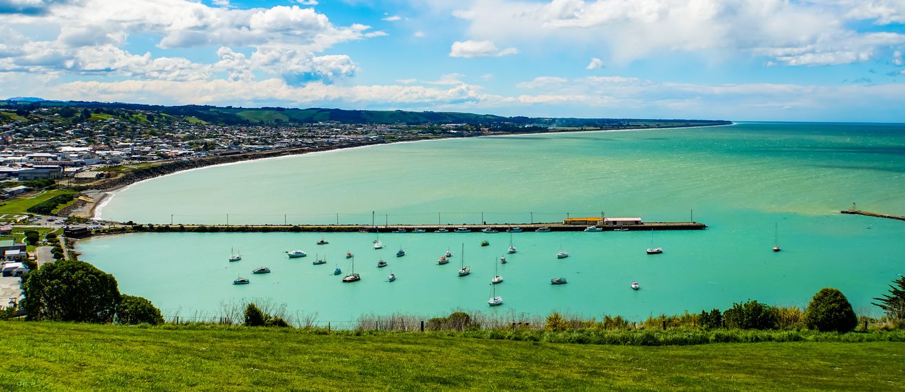 the view from the top of the hill overlooking over a harbour with boats in it and a town in the background