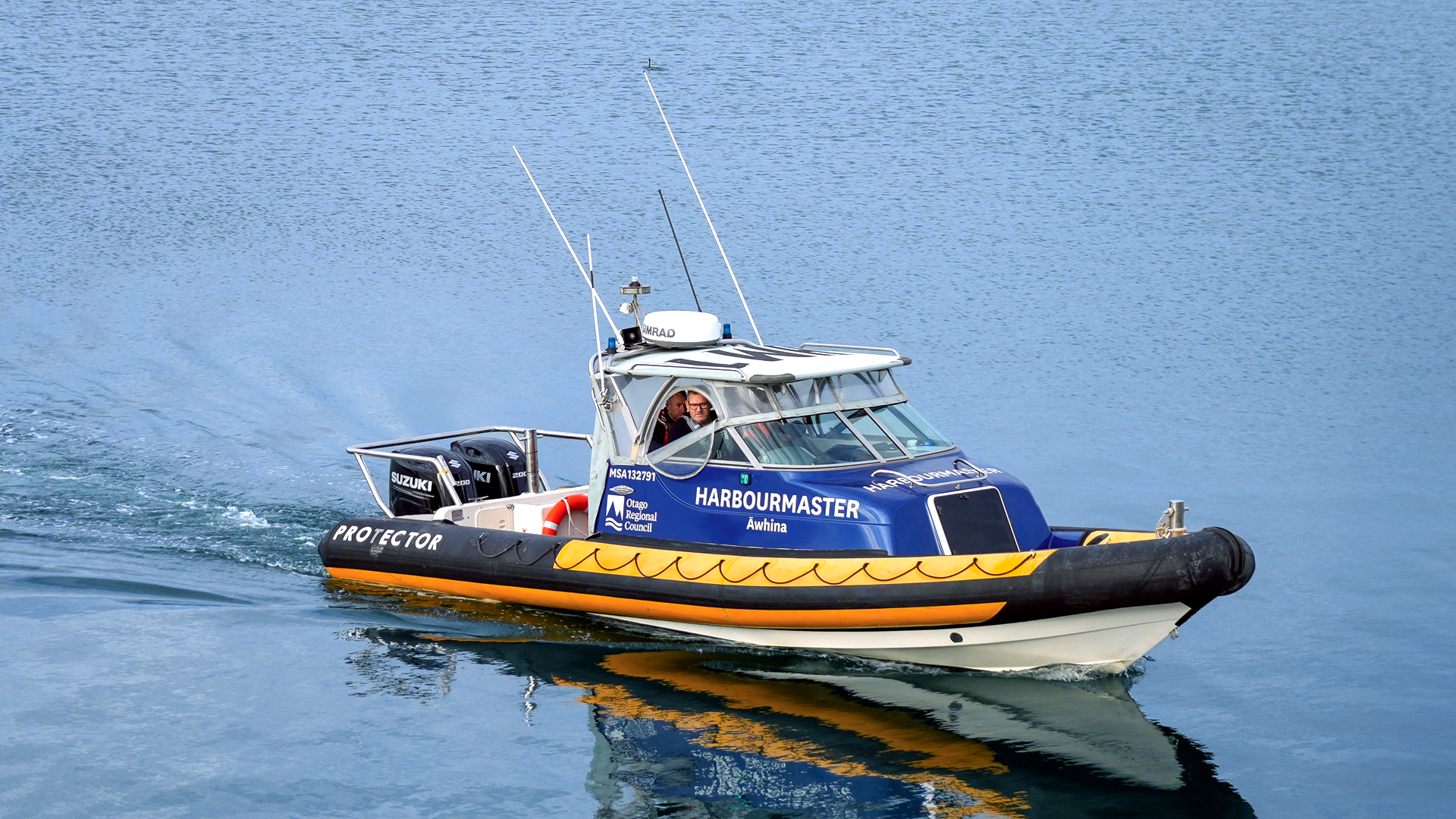 the harbourmaster's boat moving across the smooth water of the harbour