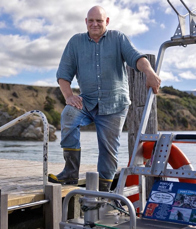 a smiling Jon Clark, looking at the camera standing on the deck of a boat