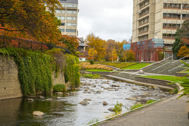 a wide stream running through an area with buildings in the background