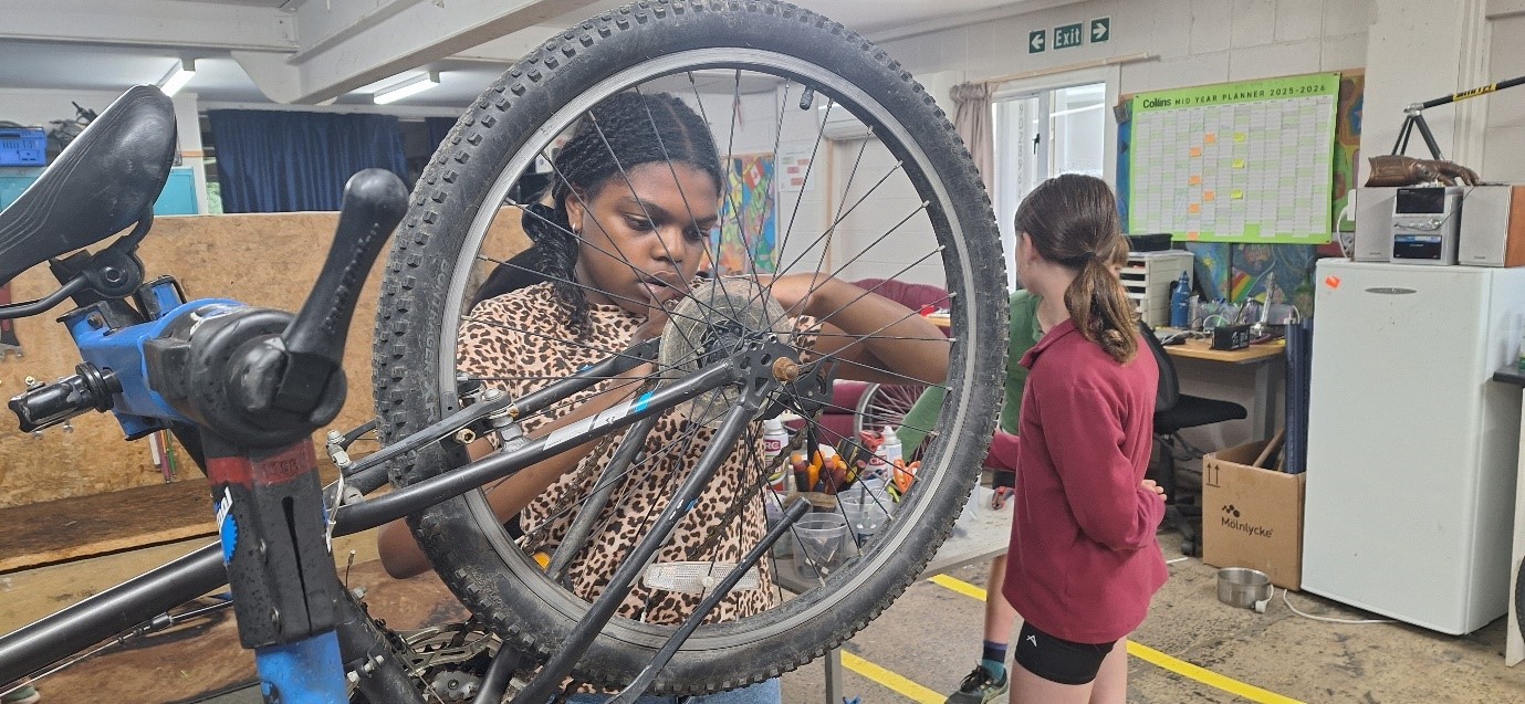 two students in a workshop area fixing bicycles