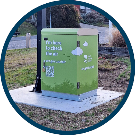 a green box on a concrete pad beside a footpath