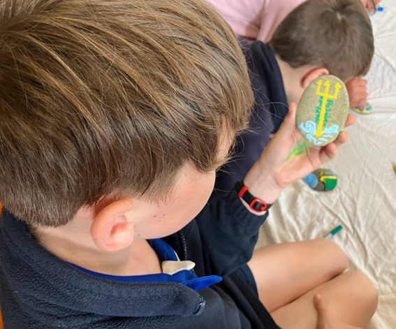 children sitting on the floor painting small rocks