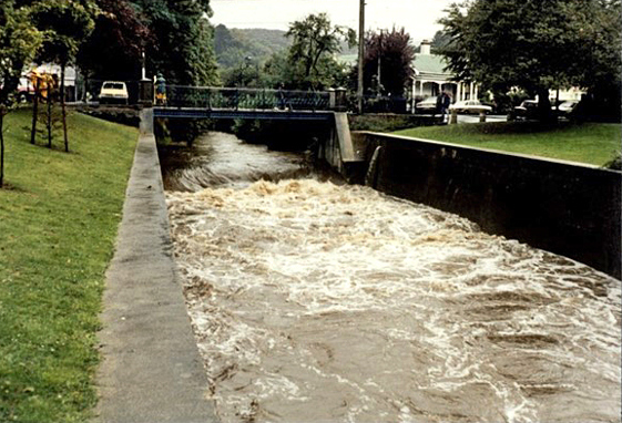 water rushing under a bridge across a concrete channel