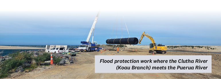 Digger carrying large black pipe doing flood protection work where the Clutha River (Koau Branch) meets the Puerua River