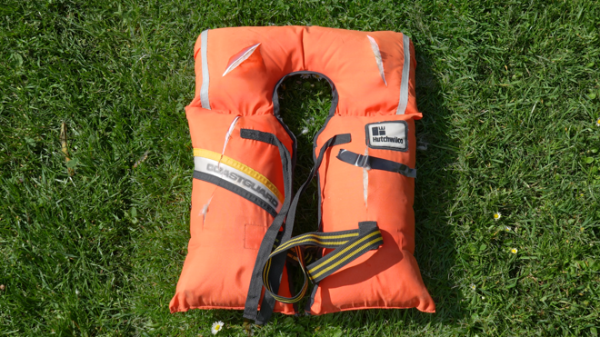 an old, torn lifejacket lying on grass