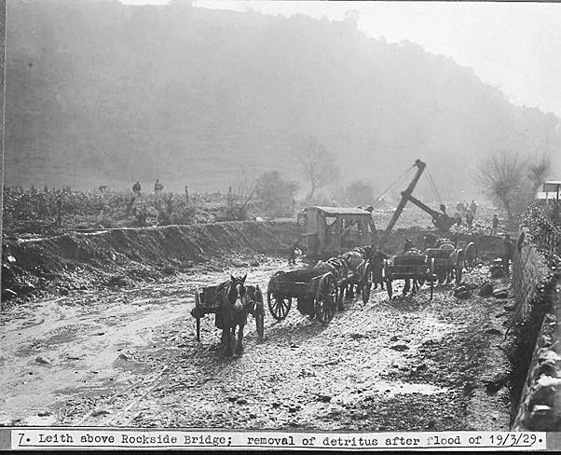 a black and white photo of horses and a wagon with the words Leith above Rockside Bridge; removal of detritus after flood of 19 March 1929