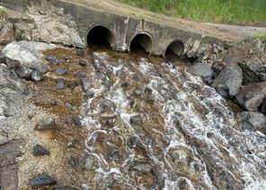 three culverts side by side with water flowing into a river, now down a slight incline with stones that stick out to help fish climb the slope