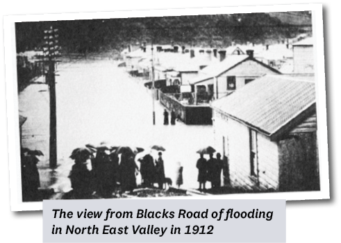 The View from Blacks Road of Flooding In North East Valley In 1912 showing people with umbrellas watching