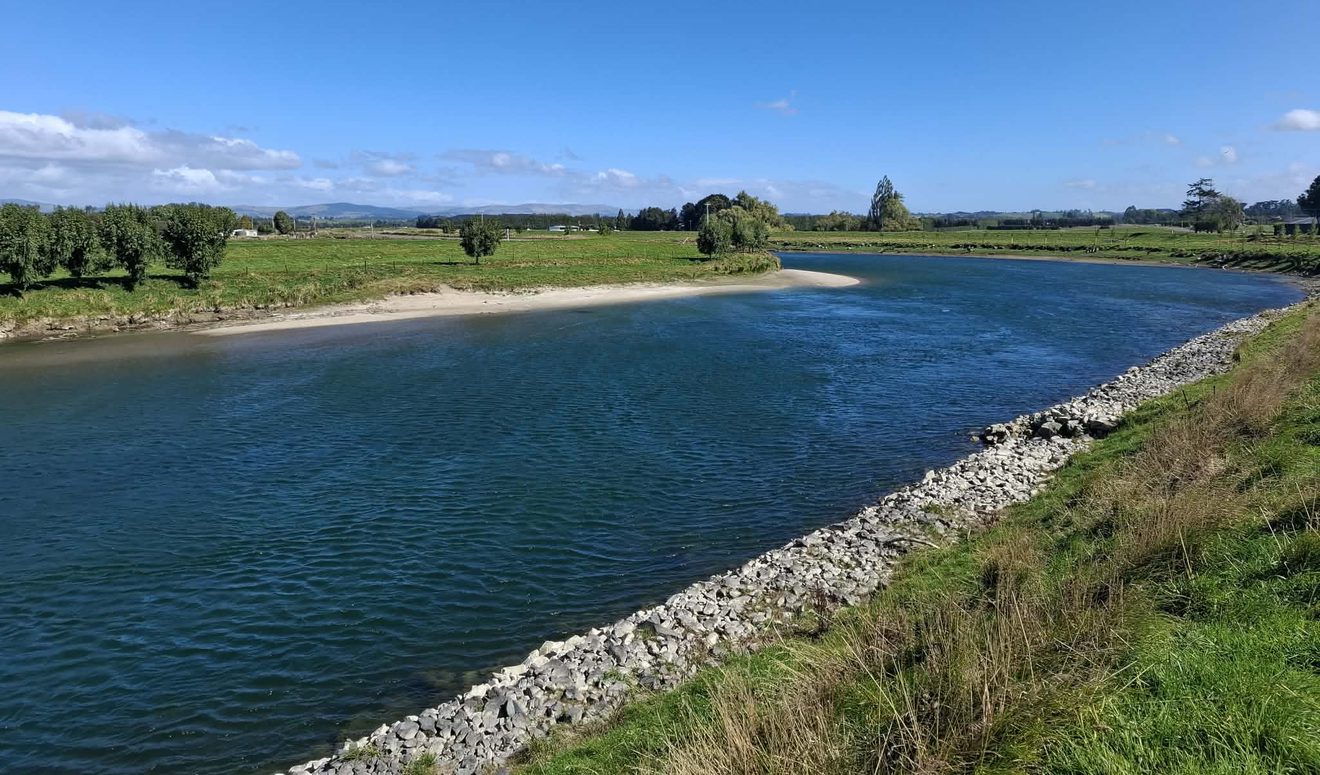 a wide river running through green grassy paddocks