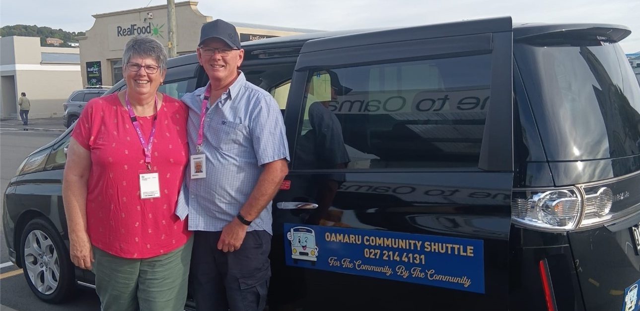 a couple standing beside a van smiling at the camera