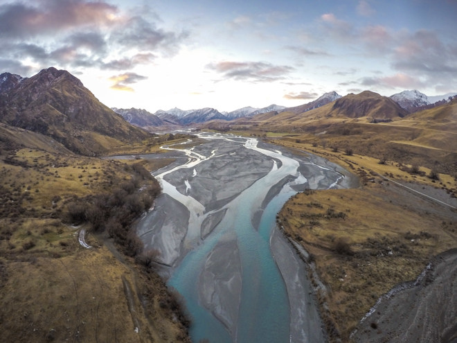 an aerial view of a braided river running through a mountain valley