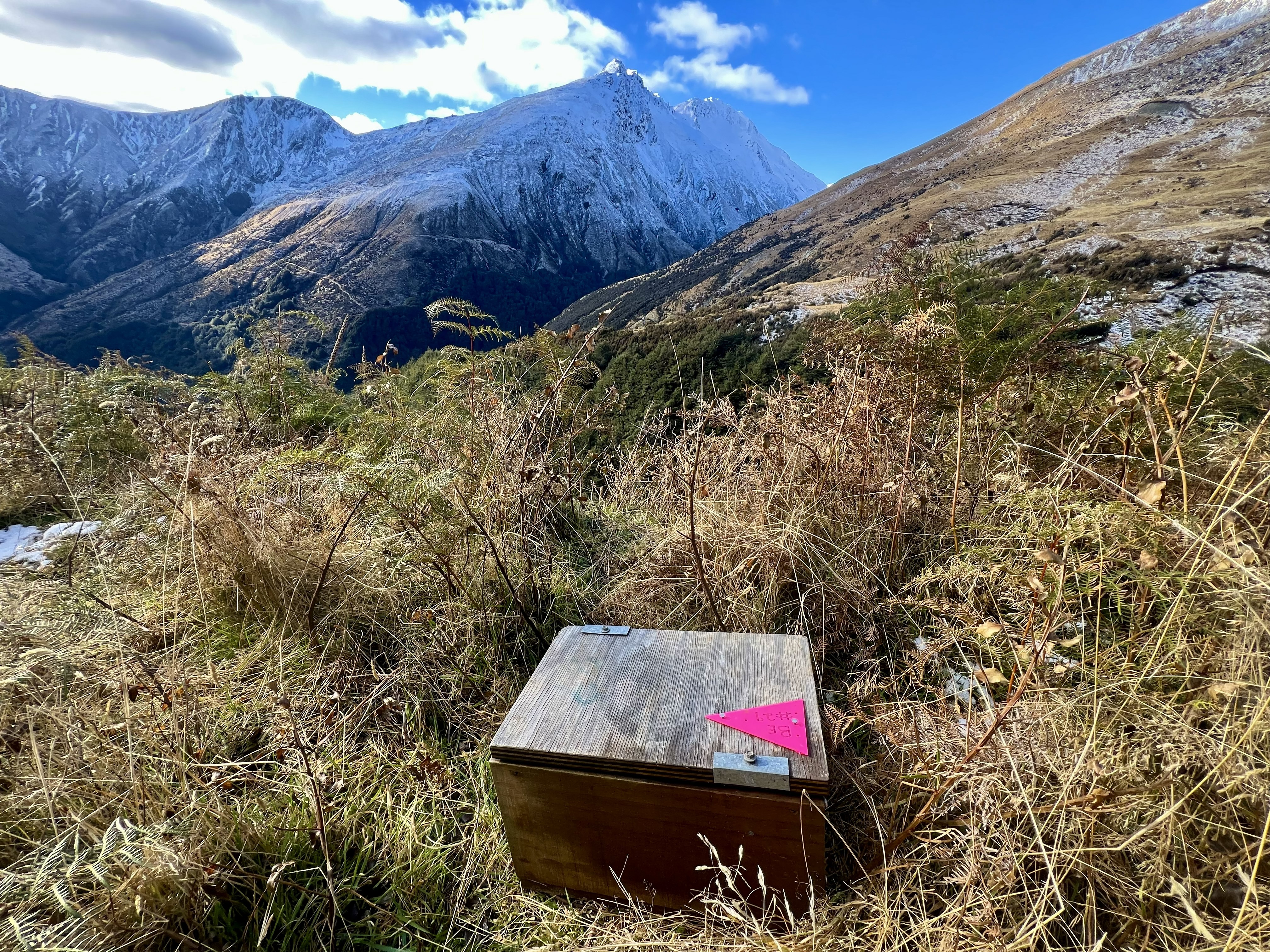 a wooden trap on the ground on a mountain, with snow-capped mountains in the background