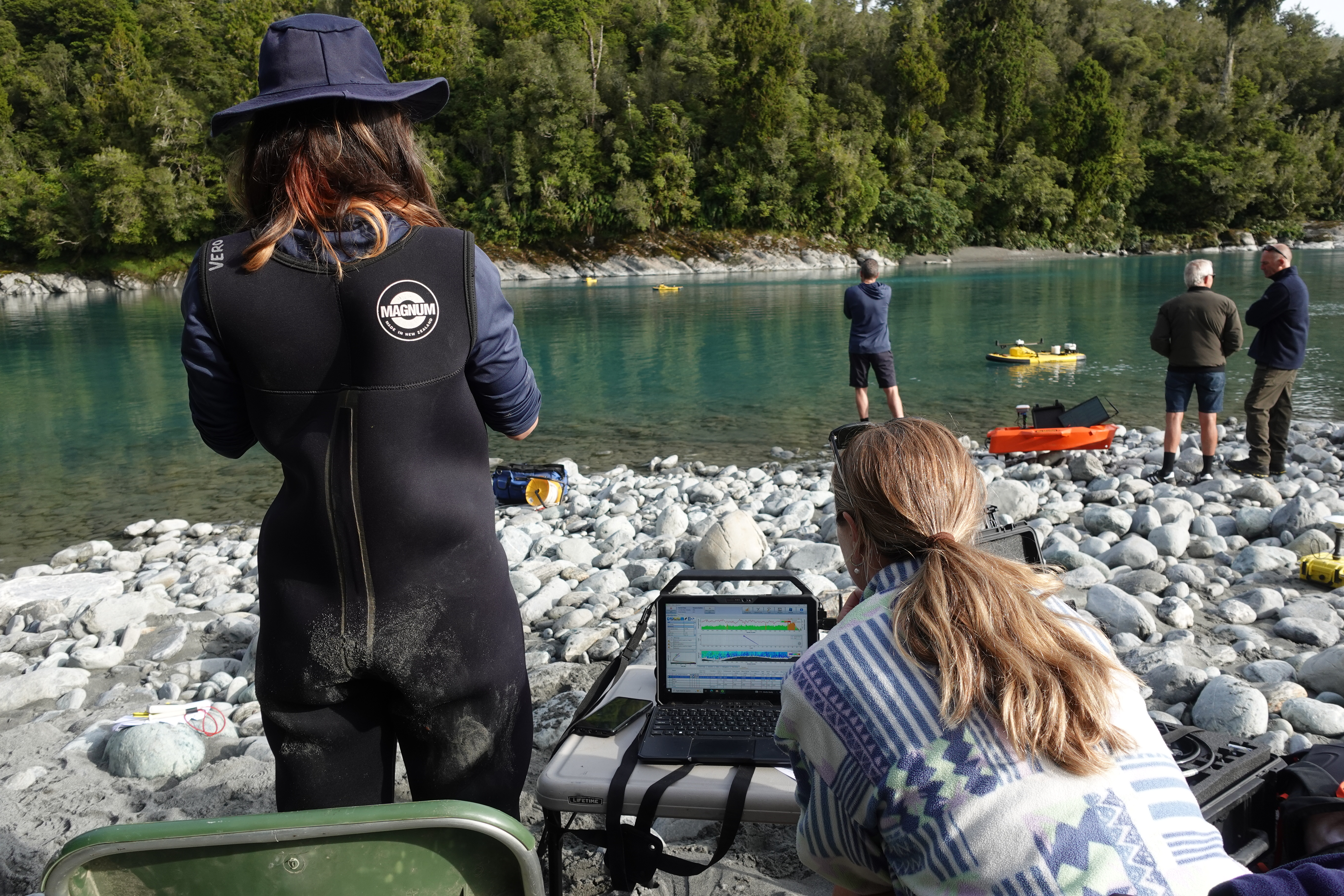 a group of people beside a river with various pieces of equipment